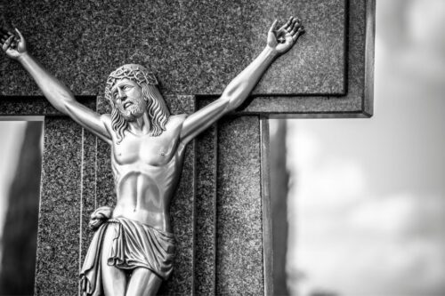 Cristo de metal sobre una cruz de una tumba hecha de mármol. Arte funerario en Aragón Valencia Castellón Teruel Marmoles y Granitos Piquer.
